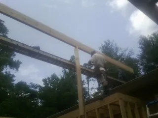 Carpenter setting a ridge beam over a new addition frame — Ice Dam Removal by Roofing Brothers in Cornish