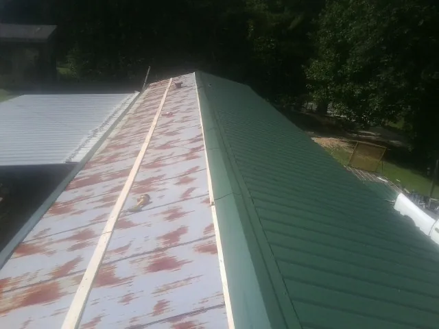 Old rusted panels beside newly installed green metal roofing — Wind Damage Roof Repair by Roofing Brothers in Cornish