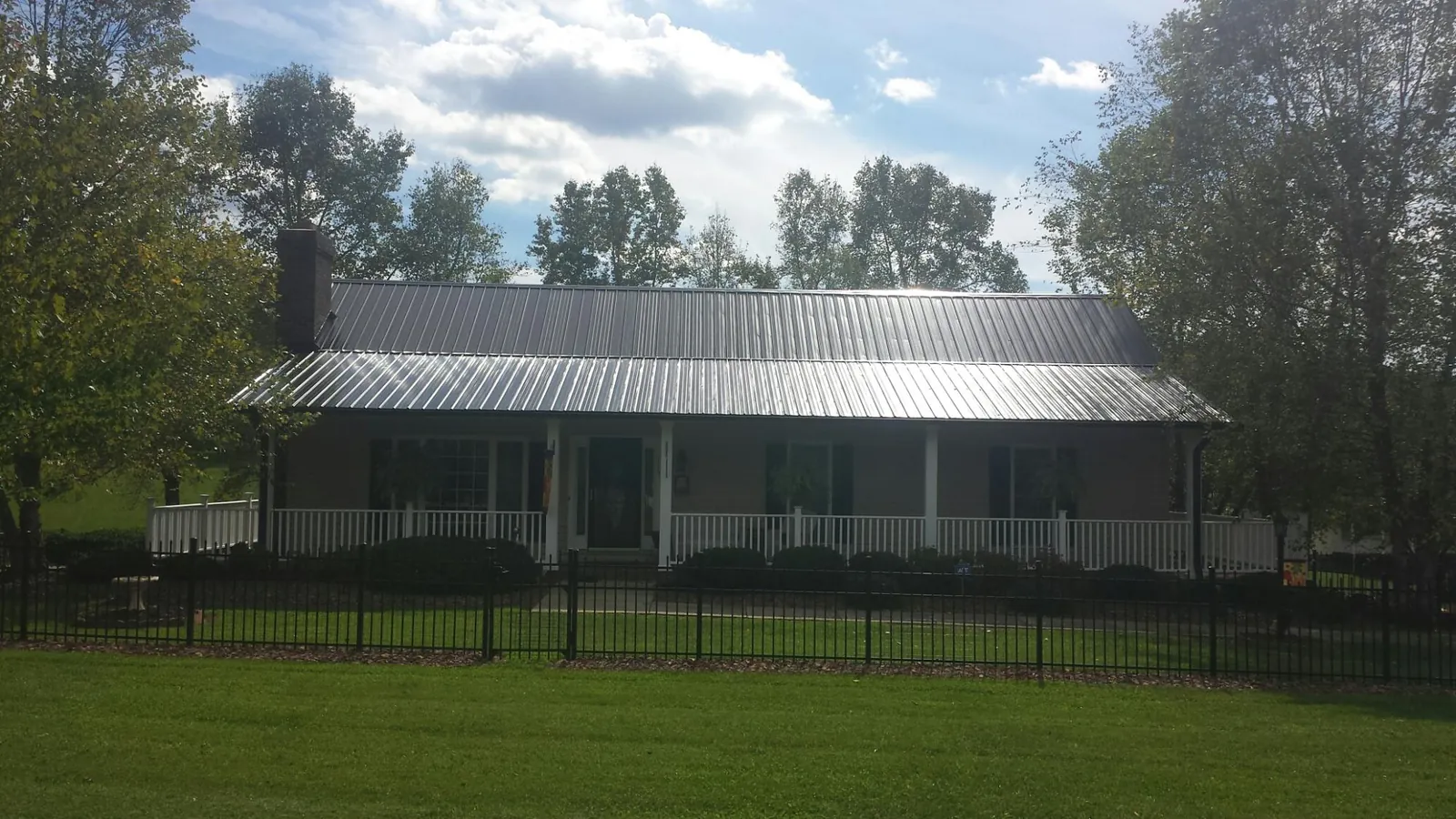 Gray metal roof on a brick ranch with a full width front porch — Gutter Guard Installation work by our crew in Cornish