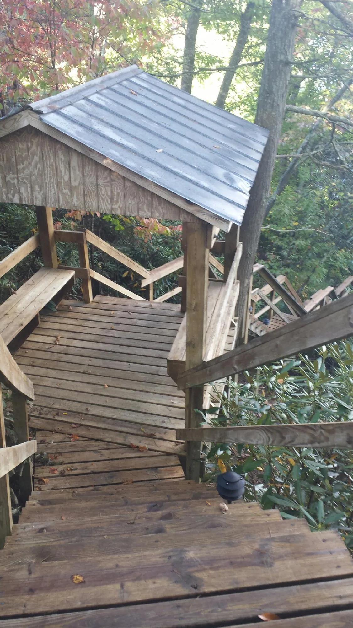 Metal roofed shelter over wooden steps on a wooded walkway — Skylight Repair & Installation work by our crew in Cornish
