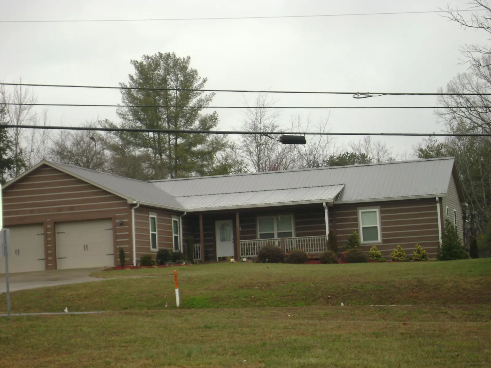 Gray metal roof on a log sided ranch home with a front porch in Cornish